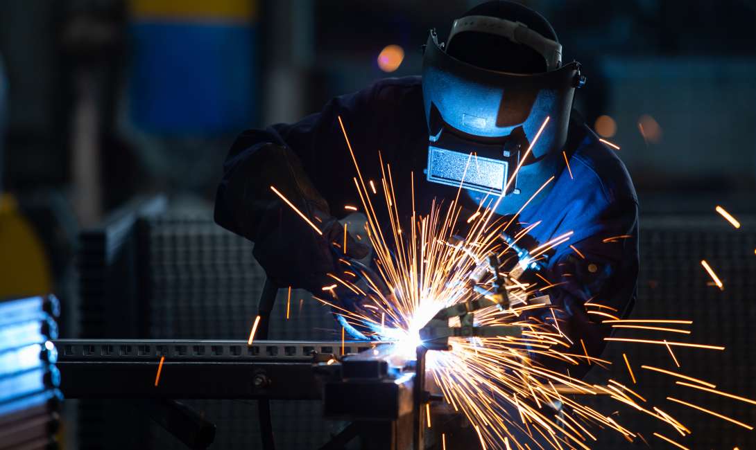 A person welding with the sparks igniting the scene with color.